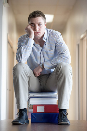an overwhelmed man sitting on binders